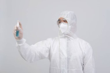 Biyolojik koruyucu üniforma, maske giyen adam doktor. Virüs bakterilerini dezenfekte etmek için el alkolü dezenfektanlı eldivenler.