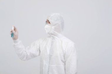 Biyolojik koruyucu üniforma, maske giyen adam doktor. Virüs bakterilerini dezenfekte etmek için el alkolü dezenfektanlı eldivenler.