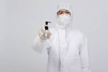 Biyolojik koruyucu giysi, maske giyen adam doktor. Virüs bakterilerini dezenfekte etmek için el dezenfektanlı eldivenler.