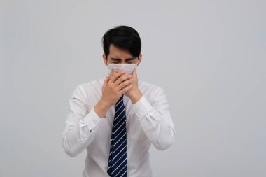 Hasta iş adamı kendini hasta hissediyor, hapşırıyor, soğuk algınlığına karşı koruyucu maske takıyor ve öksürüyor.