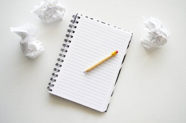 Kalem ve buruşuk kağıtlı defter. Notlar ve görevler için hazırlandı. Beyaz masada..
