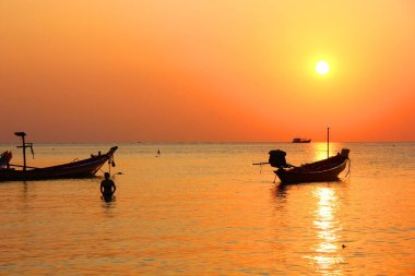 Turistler, güneş batmadan önce denizde yüzmekten hoşlanırlar. Siluet insanları deniz manzaralı ve bulutlu arka planda dinlenirler..