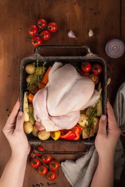 Dişi eller pişmemiş bütün tavuğu sebzelerle hazır tutarlar.