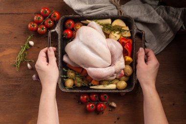 Dişi eller pişmemiş bütün tavuğu sebzelerle hazır tutarlar.