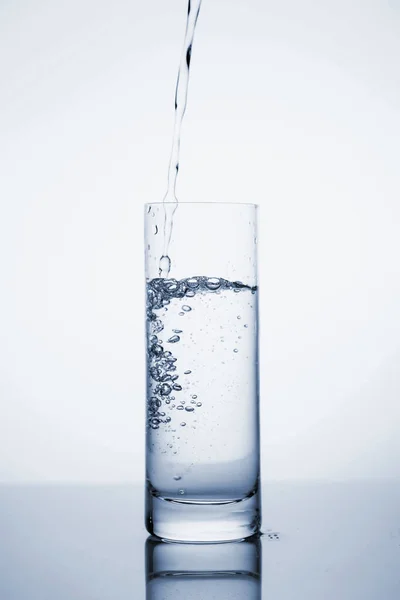 L'eau minérale claire est versée dans un verre avec de la glace . — Photo