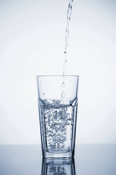 Чистая минеральная вода наливается в стакан со льдом . — стоковое фото