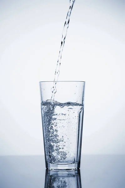 Clear mineral water is poured into a glass with ice. — 스톡 사진