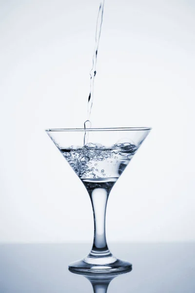 Clear mineral water is poured into a glass with ice. — Stock Photo, Image