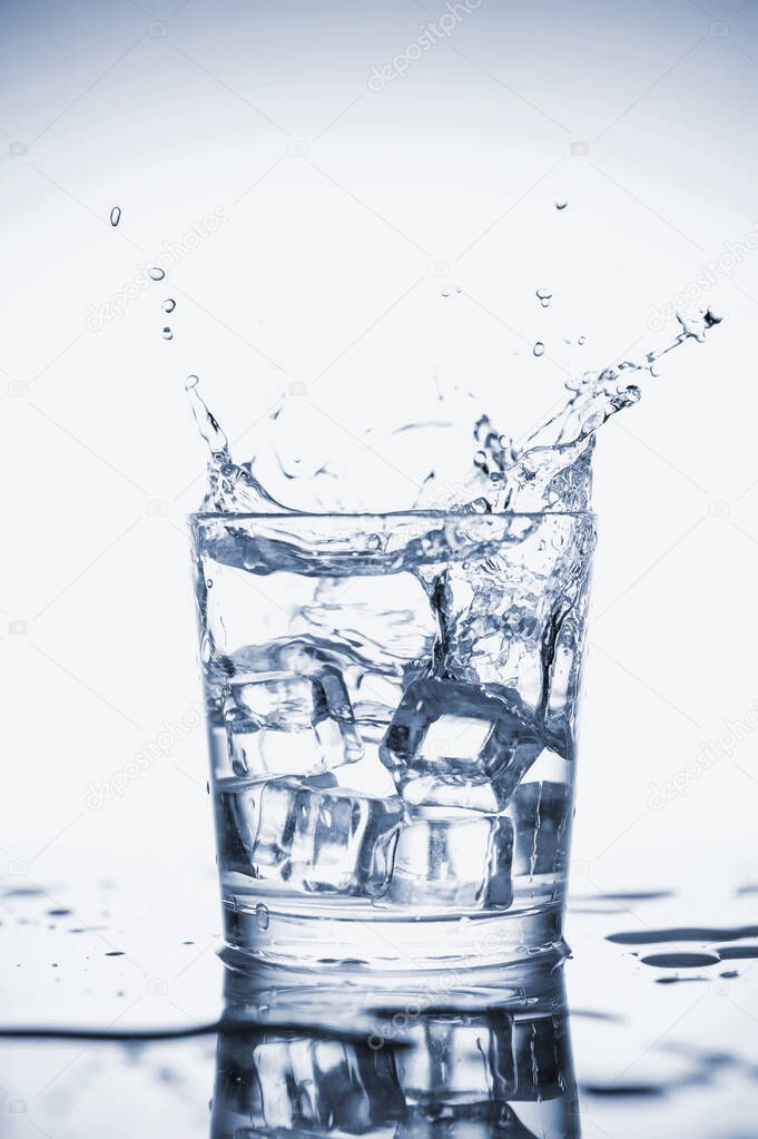 Clear mineral water splashes in a glass with ice.