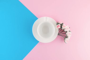 Güzel pembe ve parlak mavi pastel arka planda boş kahve fincanı ve çiçek. Üst Manzara. Düz yatıyordu. Tasarım şablonu.