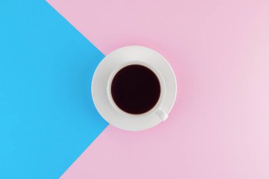 Pembe ve parlak mavi pastel arka planda bir fincan taze demlenmiş kahve. Taze tatlılar. Kremalı pasta. Pembe çikolata. Üst Manzara. Düz yatıyordu. 