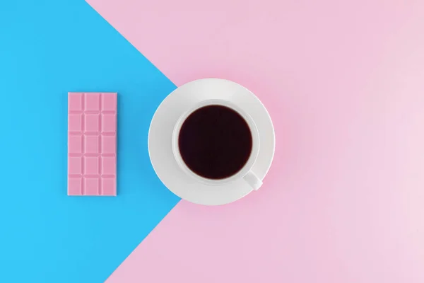 Pembe ve parlak mavi pastel arka planda bir fincan taze demlenmiş kahve. Taze tatlılar. Kremalı pasta. Pembe çikolata. Üst Manzara. Düz yatıyordu. 