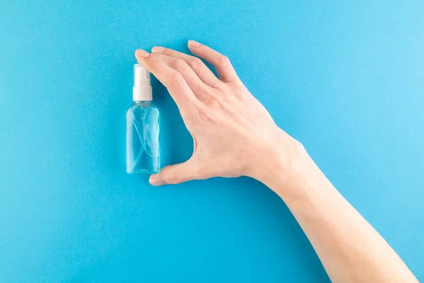 Hands hold a set of hygienic antiseptics and medications on a blue background. Antibacterial protection and self-care. Stop the spread of infection. Medical hygiene and virus protection concept.
