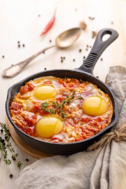 Shakshuka. Kızarmış yumurta, domates, tatlı biber ve dökme demir tavada otlar. Kahvaltı için geleneksel doğu mutfağı. Yakın plan..