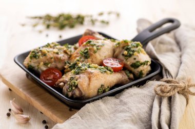 Pesto soslu kızarmış tavuk, taze otlar ve vişneli domatesler. Bireysel dökme demir bir tavada pişirilmiş. Büyük bir porsiyon yemek için hazır. Yakın plan..