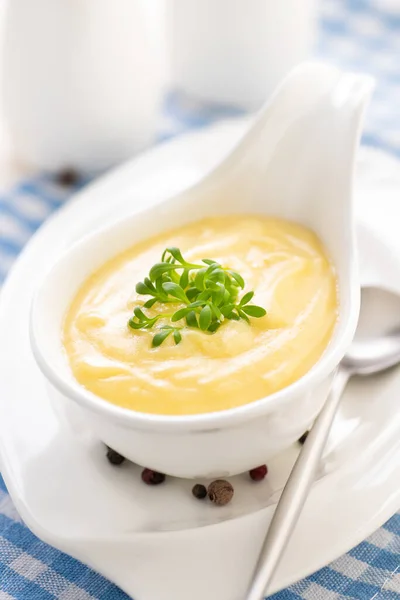Hollandaise sosu. Klasik Fransız mutfağı sosu. Sirkeli yumurta sarısı ve tereyağı emülsiyon sosu. Mavi bir peçeteyle et suyu kabında servis edilmiş. Yakın plan.