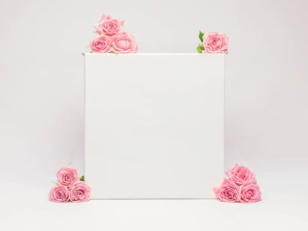 White closed box decorated with fresh flowers roses on a white background. Beautiful mockup concept for your text, logo, brand. Horizontal orientation