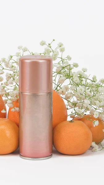 Aerosol spray can bottle on a white background with flowers gypsophila and fresh citrus fruits. Hair Care Spray Concept, metal cosmetic container, mockup for your text, logo, brand, vertical