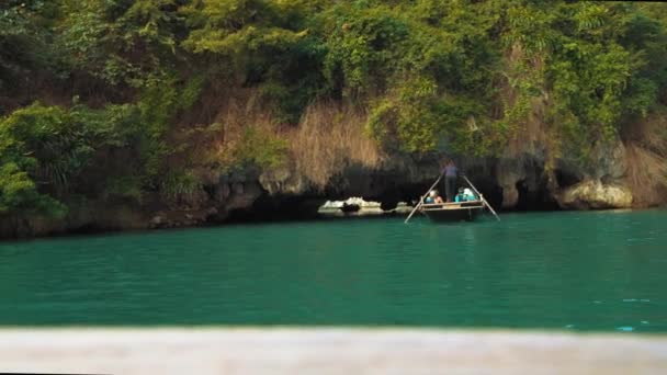 Туры на лодках проводят туристов через известняковые пещеры в бухте Ха Лонг, Вьетнам. Популярное место для туризма — стоковое видео
