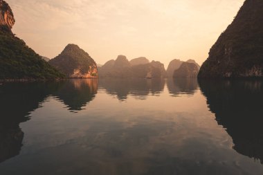 Vietnam 'da, sakin ve sakin denizleri olan güzel bir günbatımı sırasında Ha Long Körfezi. 2019 sonbaharında bir yolcu gemisinden çekilmiş.