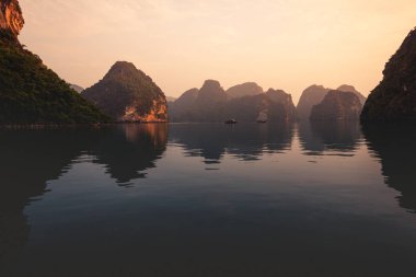 Vietnam 'da, sakin ve sakin denizleri olan güzel bir günbatımı sırasında Ha Long Körfezi. 2019 sonbaharında bir yolcu gemisinden çekilmiş.