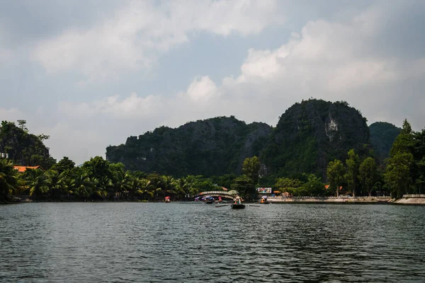 Lugareños vietnamitas reman botes de remos con sus pies para los turistas mientras viajan en un viaje en barco a través de las cuevas de piedra caliza de Ninh Binh — Foto de Stock