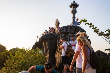 Tam Coc, Vietnam - 19 Ekim 2019: Turistler Mua Mağaraları 'nın tepesinde güzel bir gündoğumu sırasında ünlü Ejderha heykelinin yanında oturuyorlar.
