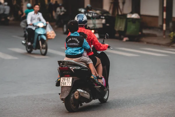 Hanoi, Vietnam - 18th October 2019: Parents take their children to school on a moped in the busy streets of Hanoi without any protection or a helmet — Stock Photo, Image