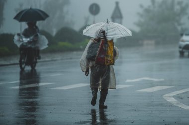 Sapa, Vietnam - 13 Ekim 2019: Şemsiye altındaki yaşlı bir Asyalı küçük Sapa kasabasındaki sağanak yağmurda kameradan uzaklaşıyor