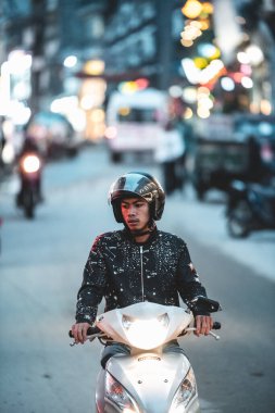 Sapa, Vietnam - 13 Ekim 2019: Asyalı bir erkek, küçük bir dağ kasabası olan Sapa, Vietnam 'da dar bir işlek sokaktan kameraya doğru scooter sürüyor