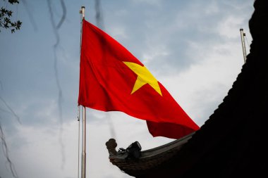 Vietnam Bayrağı Hanoi 'de bir tapınağın yanında mavi gökyüzüne karşı dalgalanıyor.
