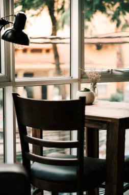 Kahve masası, müşterilerin kahve ve yemekten keyif almaları için rahatlatıcı ve huzurlu bir atmosferi olan parlak bir pencerenin yanında.