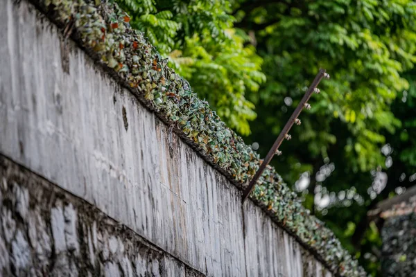 Smashed glass bottles are stuck on the top of a wall to prevent prisoners escaping from the Hanoi Hotel political prison in Vietnam — Stock Photo, Image