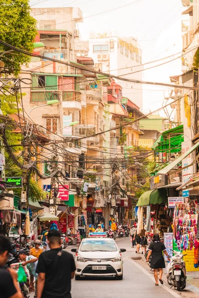 Hanoi, Vietnam - 11 de octubre de 2019: Mirando por una calle concurrida en Hanoi durante el atardecer con el sol al fondo y la gente en las calles concurridas — Foto de Stock