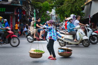 Hanoi, Vietnam - 11 Ekim 2019: Asya 'nın Hanoi kentindeki işlek bir yoldan tahta bir sopayla mal taşıyan Asyalı kadın