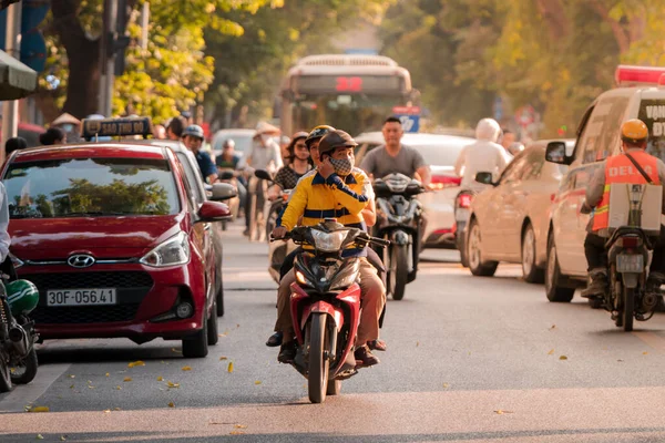 Hanoi, Vietnam - 11 de octubre de 2019: Un conductor y su pasajero conducen en un ciclomotor por las concurridas calles de Hanoi durante el atardecer conduciendo hacia la cámara — Foto de Stock