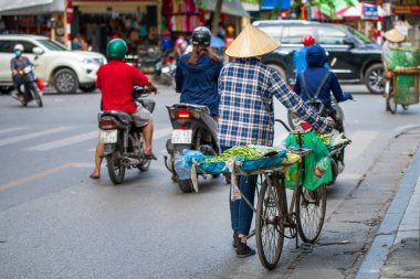 Hanoi, Vietnam - 11 Ekim 2019: Bir sokak yemeği satıcısı bisikletle şehirde satılık meyve topluyor