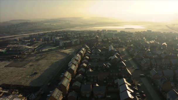 Aerial drone panning down street of new homes built on the Waverley residential estate in Rotherham, South Yorkshire druing a golden sunrise — Stock Video