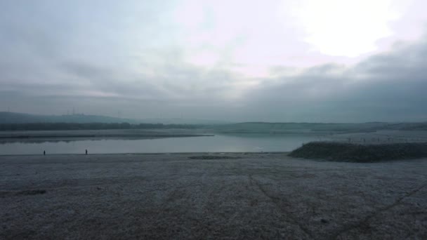 Красивая воздушная сковорода вдоль озера Вейверли в холодное морозное зимнее утро с людьми, гуляющими по озеру утром — стоковое видео