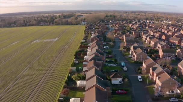 Légi felvétel egy lakótelepről egy nagy mező mellett egy alacsony napon és egy arany napfelkeltekor Hornsea-ban, East Yorkshire-ben, Uk-ban — Stock videók