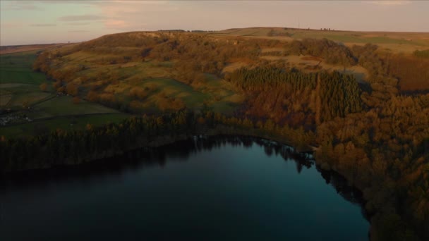 Rekaman udara terbang di atas danau Agden Reservoir saat matahari terbenam di atas desa Bradfield di Sheffield, Peak District National Park, Yorkshire dan Derbyshire, Inggris. Desember 2019 . — Stok Video