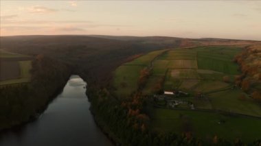 Sheffield, Peak District Ulusal Parkı, Yorkshire ve Derbyshire, Uk 'ta günbatımında yeşil yemyeşil İngiliz kırsalındaki eski bir çiftlik evinin hava görüntüleri. Aralık 2019.