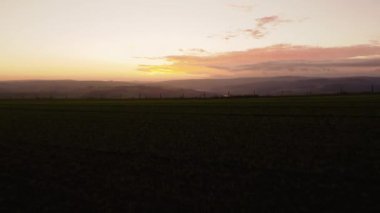 Kış günbatımında, güzel pembe ve turuncu gökyüzü ve Peak District Ulusal Parkı 'ndaki bulutlarla birlikte çimenli bir tarlanın üzerinde İngiliz kırsal siluetinin hava gösterimi, Uk