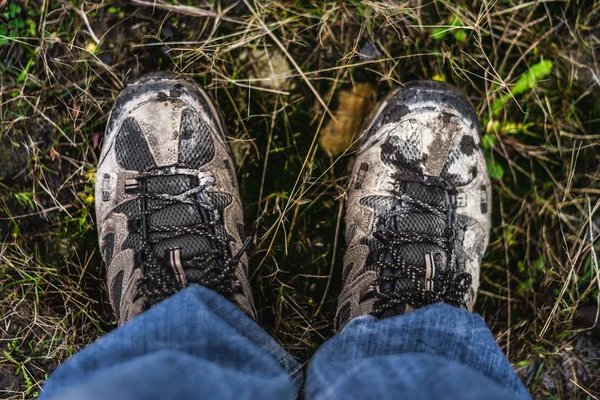 A pair of males walking shoes covering in mud stood on some grass shot from above looking directly down — Stock Photo, Image