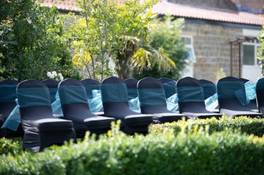 Chairs lined up for guests at outdoor wedding in the summer months with bright lush green grass