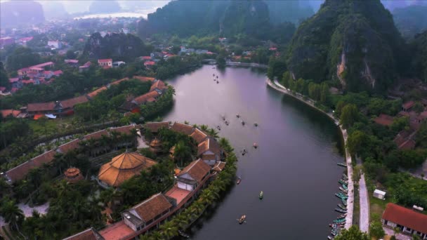 Top down luchtfoto van roeiboten nemen toeristen rond de bezienswaardigheden van Ninh Binh, Noord-Vietnam in de buurt van het kleine dorpje Tam Coc. oktober 2019 — Stockvideo