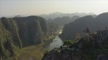 Turistler, Kuzey Vietnam 'daki Ninh Binh bölgesinde güzel bir günbatımında ünlü Yalancı Ejder Dağı heykeline tırmanıyorlar.