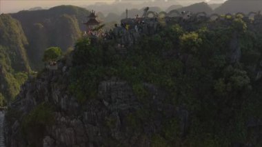 Turistler, Kuzey Vietnam 'daki Ninh Binh bölgesinde güzel bir günbatımında ünlü Yalancı Ejder Dağı heykeline tırmanıyorlar.