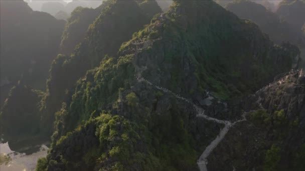 Turistas escalam a famosa Estátua da Montanha Dragão Mentiroso durante um belo pôr do sol na província de Ninh Binh, no norte do Vietnã — Vídeo de Stock