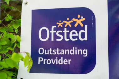 Aldershot, İngiltere - 25 Nisan 2019: Aldershot, İngiltere 'deki bir ortaokul bahçesindeki çitin üzerindeki Ofsted tabelasına yakın çekim